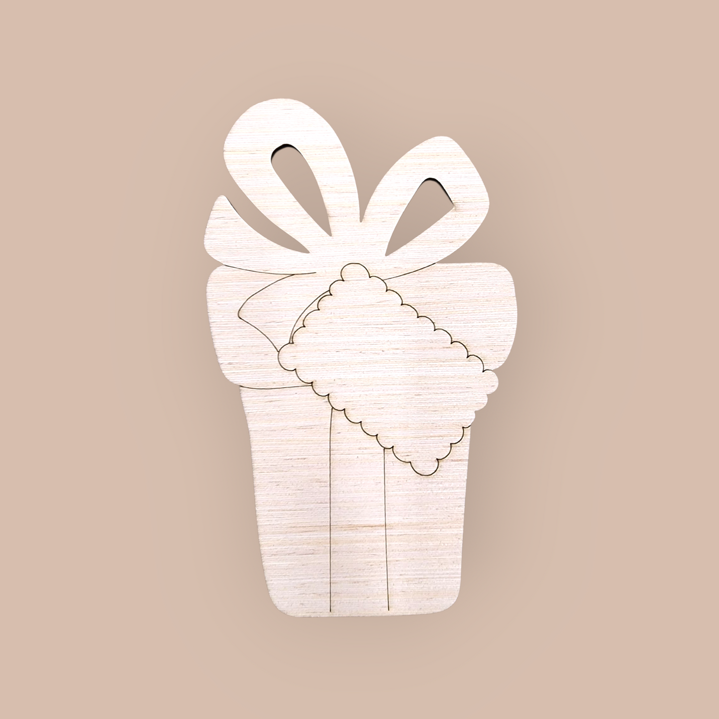 Unfinished wood ornament blank with an engraved design of a Christmas present, bow, and gift tag.