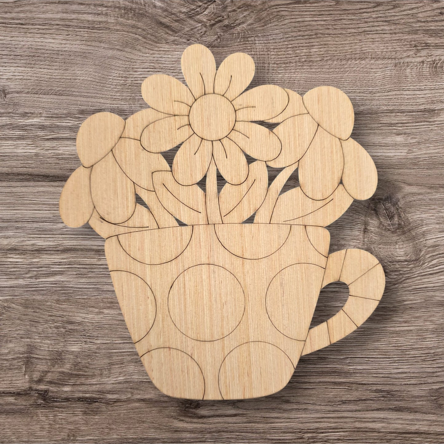 Wooden cutout of a teacup with flowers on a wooden surface