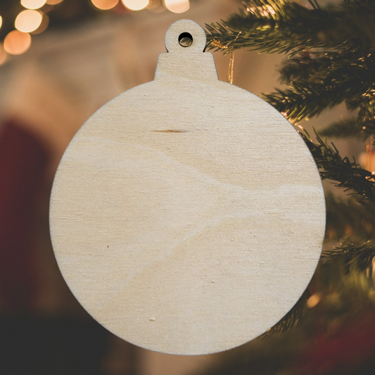 Unfinished round wood ornament blank hanging on a Christmas tree.
